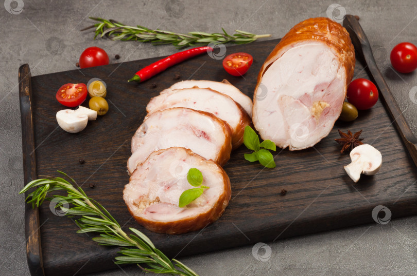 Скачать рулетики из варено-копченой курицы на темной деревянной доске фотосток Ozero