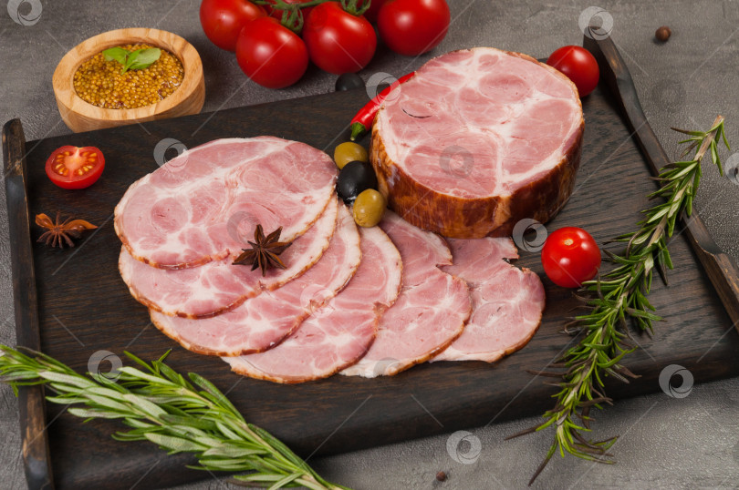 Скачать деликатесы из вареной и копченой свинины на темной деревянной доске фотосток Ozero