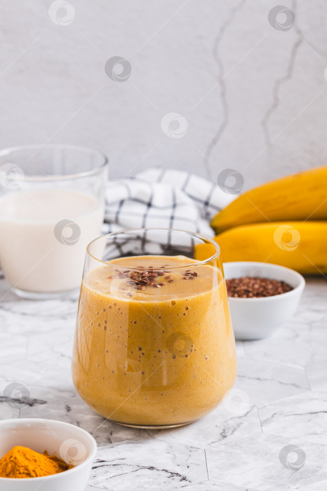 Скачать Смузи из кокосового молока, банана, куркумы и семян льна в стеклянной вертикальной упаковке фотосток Ozero