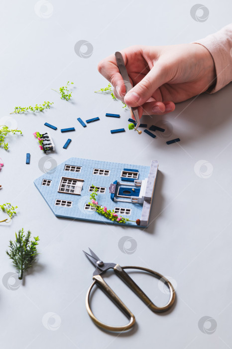 Скачать Детская рука украшает фигурку домика вертикальным изображением растения фотосток Ozero