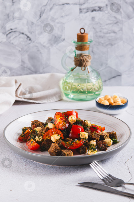 Скачать Салат из ржаного хлеба, помидоров черри и копченого сыра на тарелке на столе, вид сверху фотосток Ozero