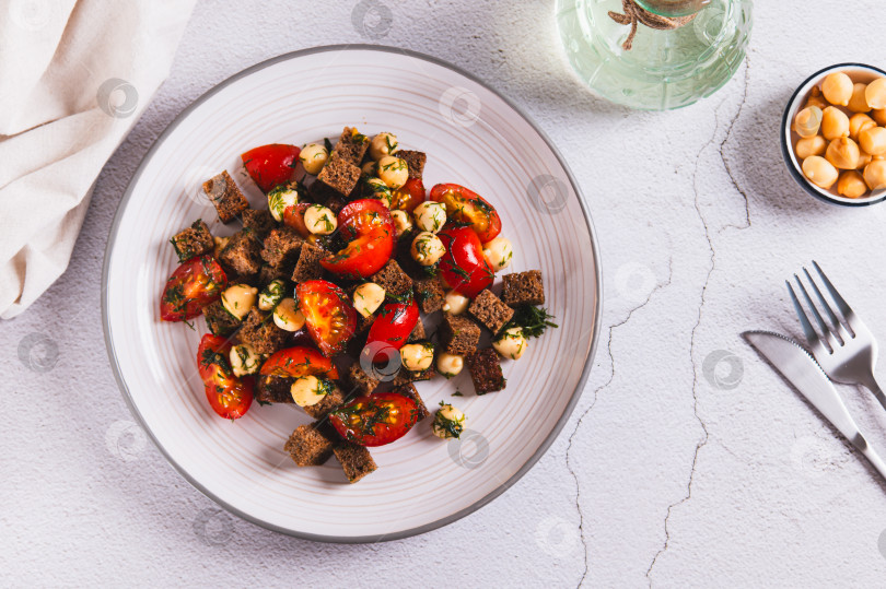 Скачать Салат из ржаного хлеба, помидоров черри и копченого сыра на тарелке на столе вид сверху фотосток Ozero