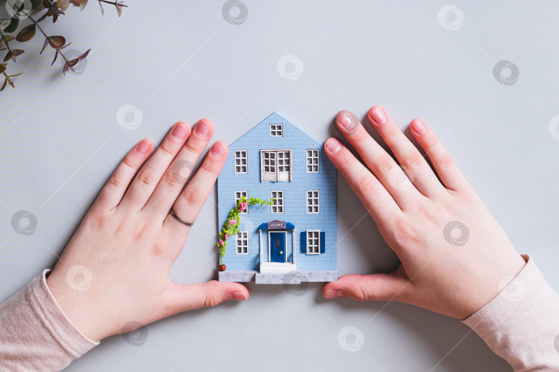 Скачать Фигурка домика и детские ручки на синем фоне, концепция комфорта фотосток Ozero