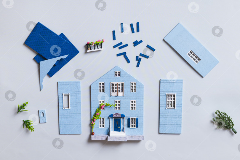 Скачать Детали для сборки миниатюрной модели дома на синем фоне, вид сверху фотосток Ozero