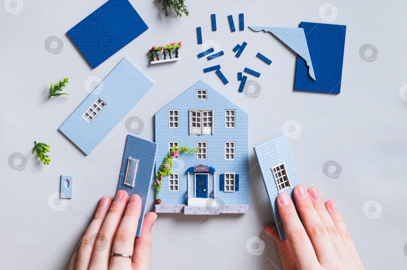 Скачать Девочка собирает миниатюрный игрушечный домик из деталей на синем фоне вид сверху фотосток Ozero