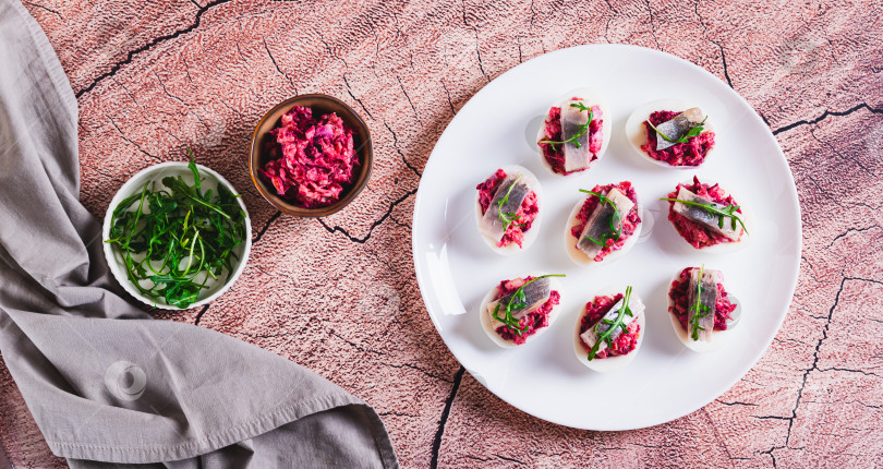 Скачать Яйца, запеченные с овощным салатом, кусочком сельди и рукколой на тарелке вид сверху веб-баннер фотосток Ozero