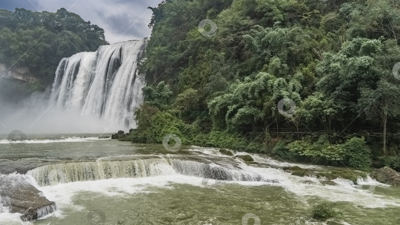 Скачать Живописный тропический водопад. Со скалы стекают потоки белой воды. фотосток Ozero