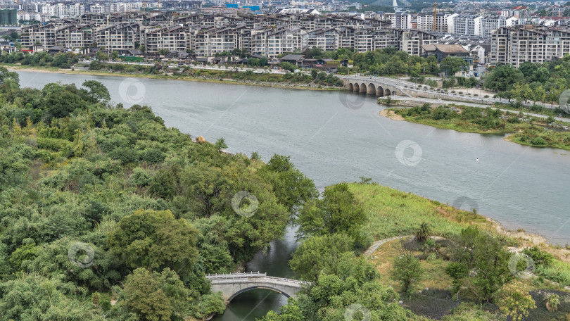 Скачать Современный городской пейзаж. Берега реки покрыты пышной зеленой растительностью. фотосток Ozero