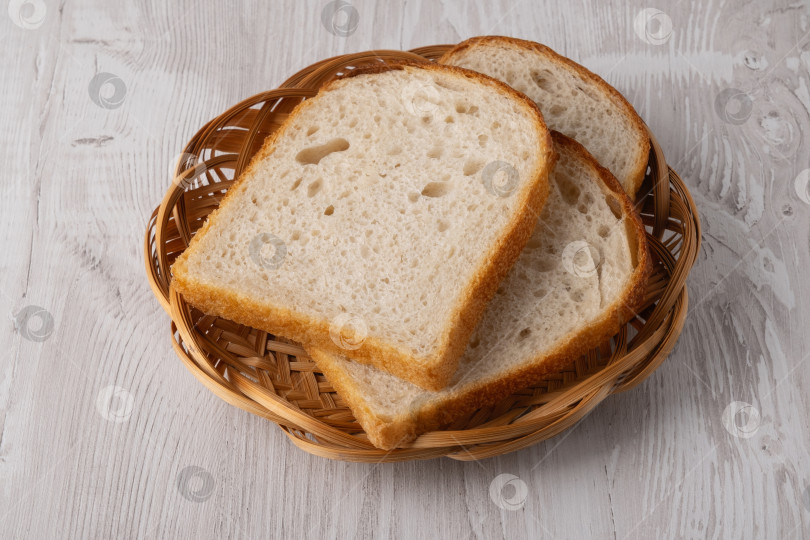 Скачать Ломтики хлеба подаются в круглой корзинке на деревянном столе фотосток Ozero