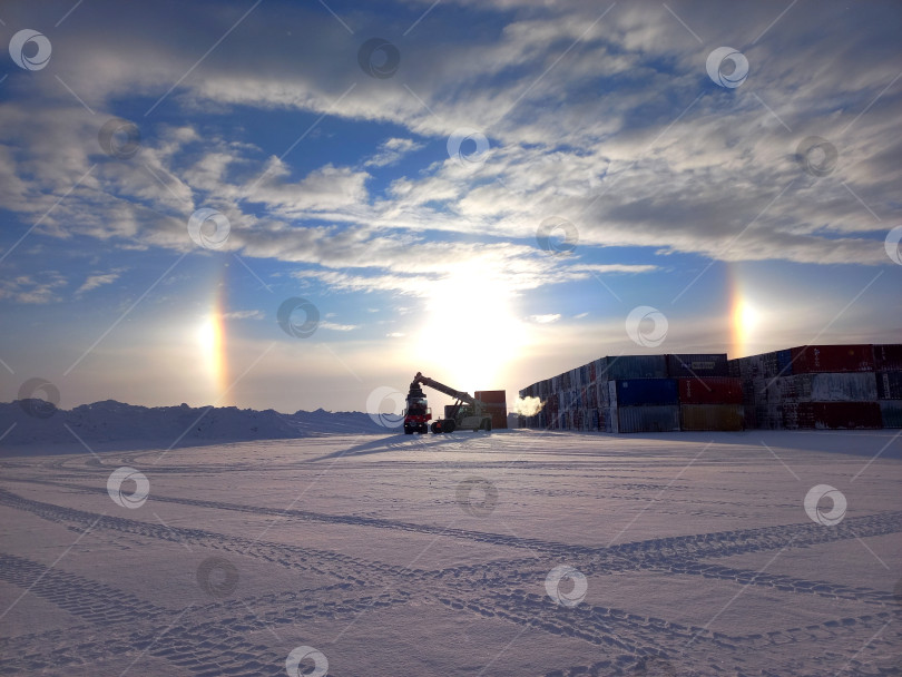 Скачать Погрузка контейнеров на заснеженной открытой площадке под сводами радуги. фотосток Ozero