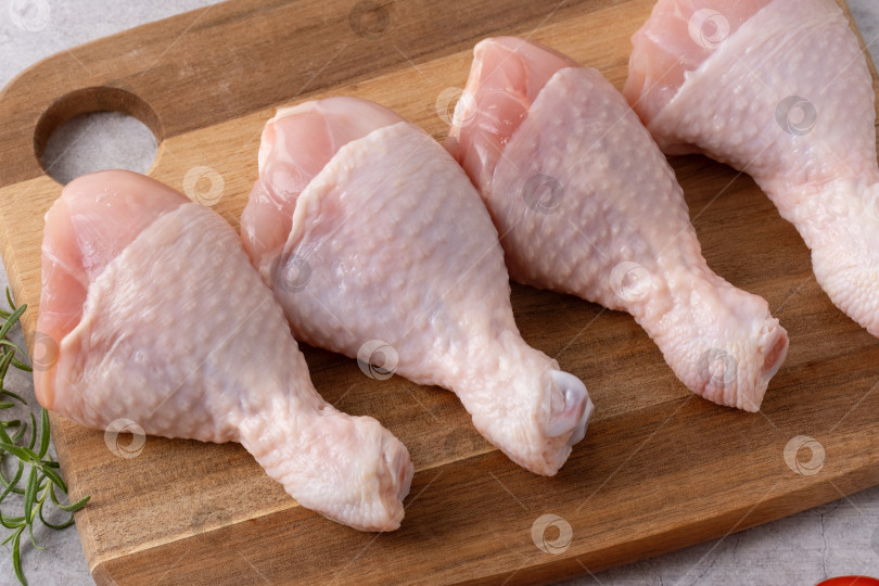 Скачать Свежие куриные ножки, разложенные на деревянной разделочной доске, готовые к приготовлению в кухонных условиях фотосток Ozero