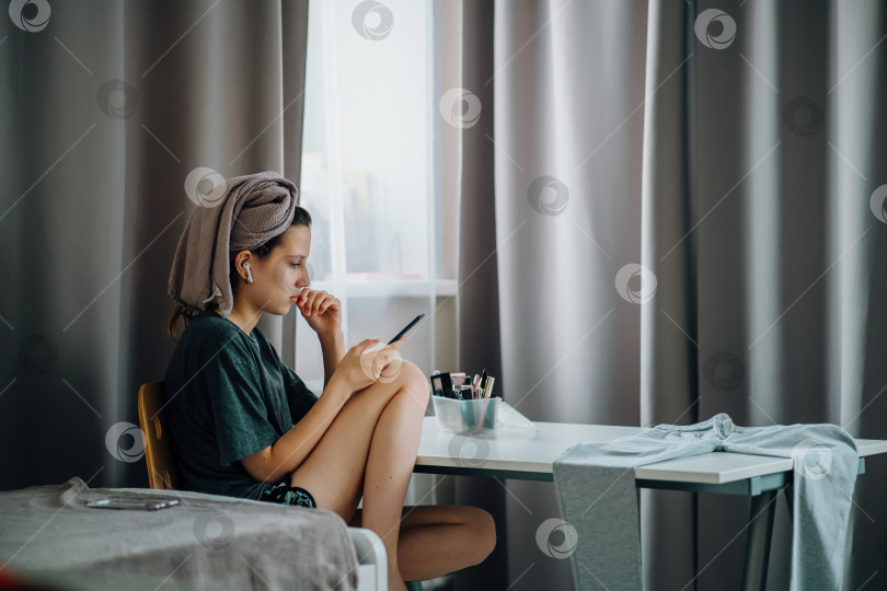 Скачать Девушка-подросток с телефоном сидит за столом дома на широком снимке фотосток Ozero
