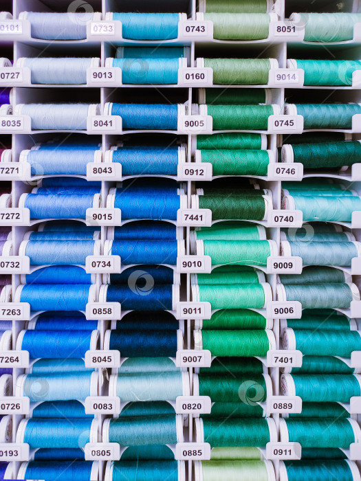 Скачать Ряды разноцветных катушек с нитками на текстильном фоне фотосток Ozero