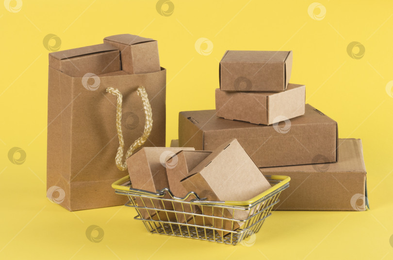 Скачать Картонные коробки разных размеров, корзины и пакеты на желтом фоне. Доставка с торговых площадок и интернет-магазинов фотосток Ozero