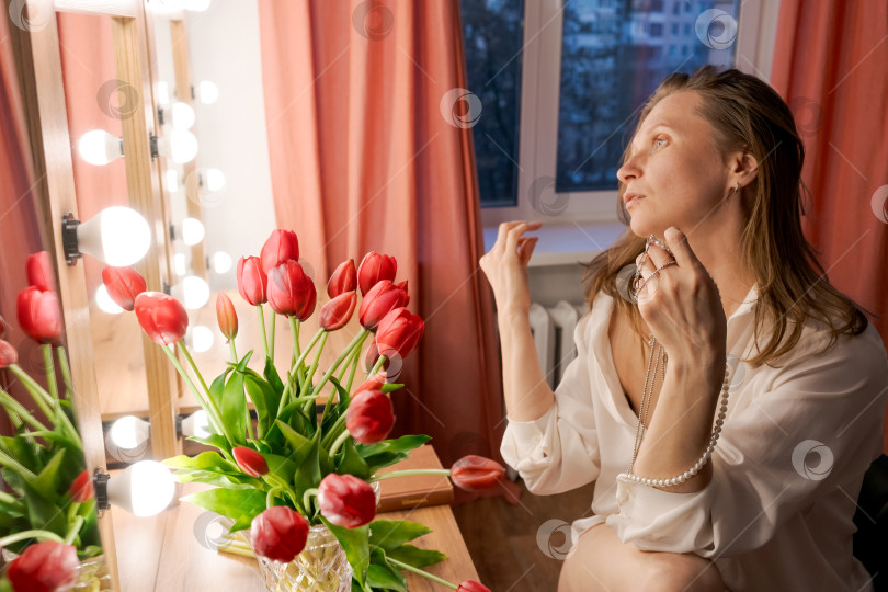 Скачать Женщина, Смотрящая В Окно С Жемчужным Ожерельем И Красными Тюльпанами фотосток Ozero