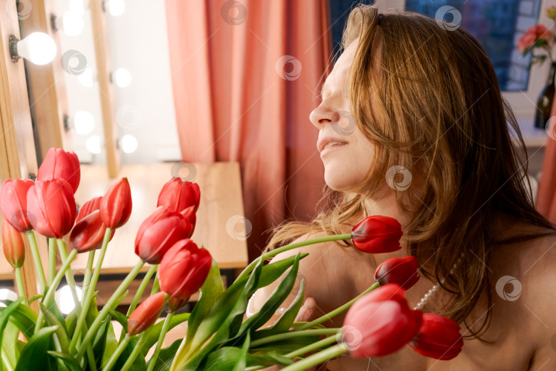 Скачать Женский профиль среди красных тюльпанов с жемчужным ожерельем фотосток Ozero