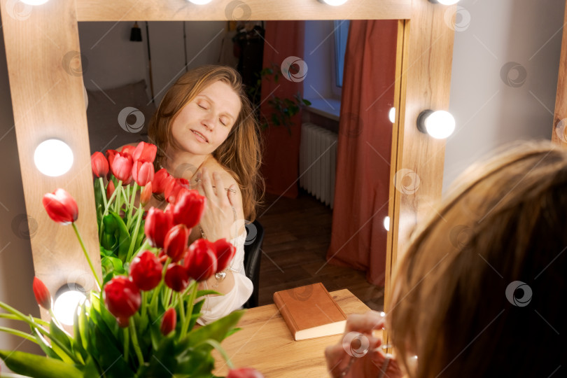 Скачать Женщина, касающаяся плеча в отражении зеркала с тюльпанами фотосток Ozero
