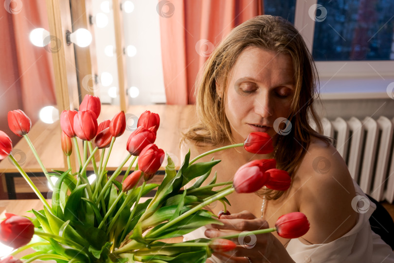 Скачать Женщина, смотрящая сверху вниз на тюльпаны с жемчужным ожерельем фотосток Ozero