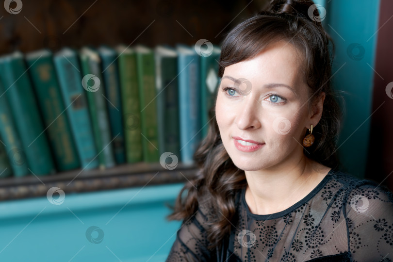 Скачать Элегантная женщина, смотрящая в сторону, позирует в классической винтажной библиотеке фотосток Ozero