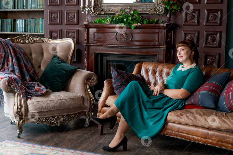 Скачать Утонченная зрелая женщина в зеленом платье в роскошном классическом интерьере фотосток Ozero