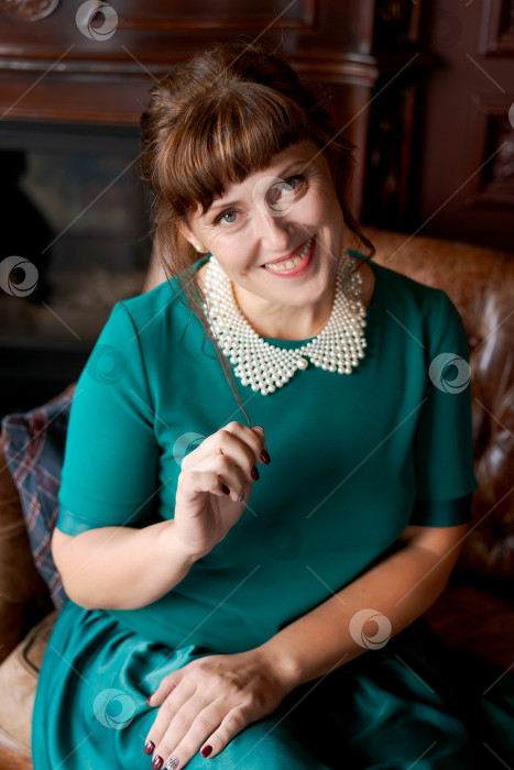 Скачать Сияющая зрелая женщина улыбается и играет с волосами в роскошном интерьере фотосток Ozero