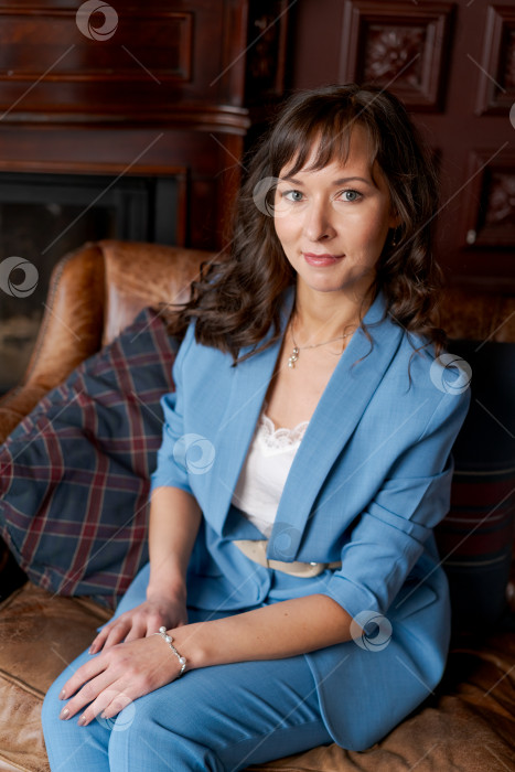 Скачать Элегантная деловая женщина в синем костюме Нежно улыбается на кожаном диване фотосток Ozero