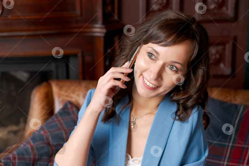 Скачать Сияющая деловая женщина разговаривает по смартфону в элегантном офисе фотосток Ozero