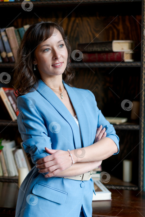 Скачать Уверенная в себе деловая женщина в синем костюме стоит в классическом библиотечном кабинете фотосток Ozero