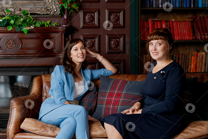Скачать Две профессиональные женщины-деловые партнерши сидят на диване в классическом офисе фотосток Ozero