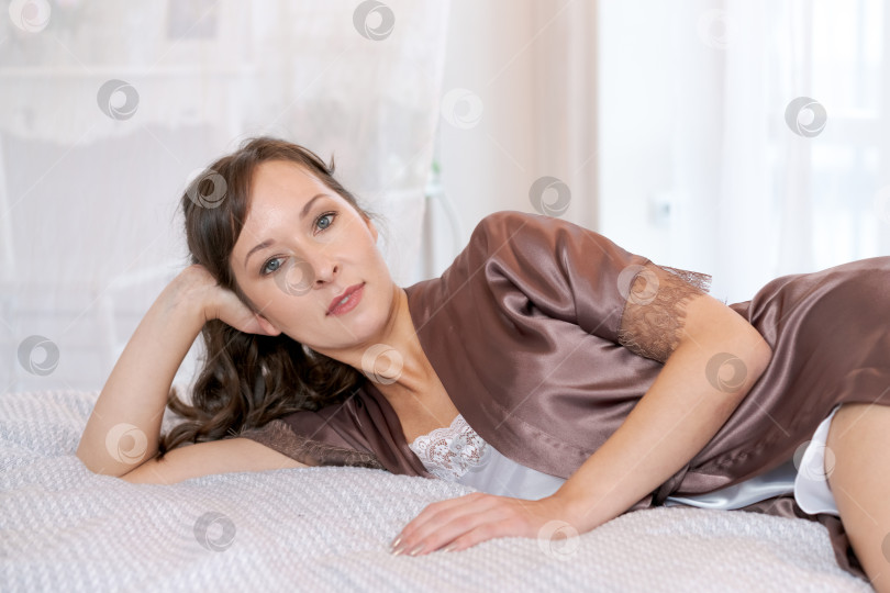 Скачать Крупный план красивой женщины в шелковом халате, отдыхающей на кровати в ярком интерьере фотосток Ozero