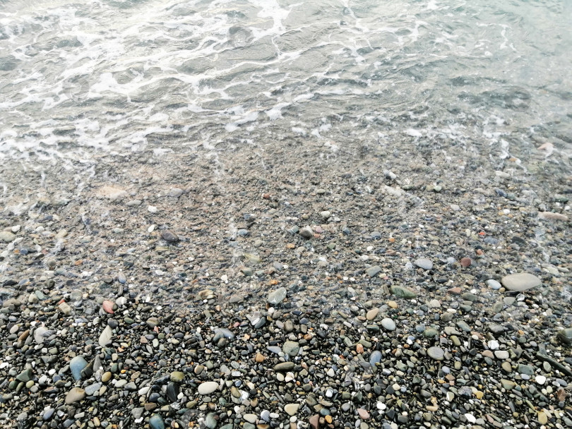 Скачать Берег моря, спокойные волны набегают на пляж с мелкой галькой фотосток Ozero