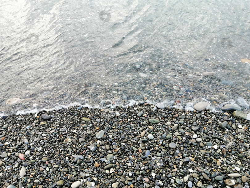 Скачать Берег моря, спокойные волны набегают на пляж с мелкой галькой фотосток Ozero