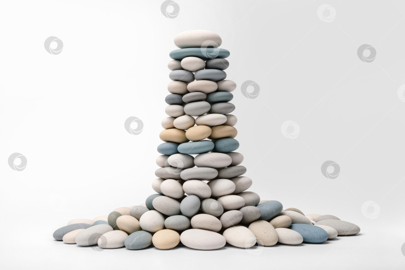 Скачать Стопка гладких овальных камешков разных цветов и размеров, собранных в башню, выделенную на белом фоне, копировальное пространство, минимализм фотосток Ozero