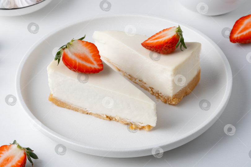 Скачать Ломтики чизкейка со свежей клубникой на белой тарелке на кухне в дневное время фотосток Ozero