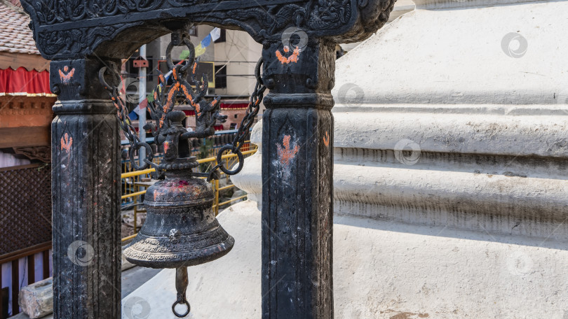 Скачать Древний колокол из черного металла подвешен на цепях между каменными колоннами. фотосток Ozero