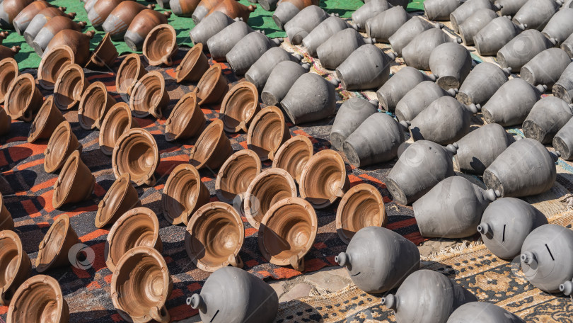 Скачать Глиняные горшки ручной работы расставлены рядами на циновках, расстеленных на земле. фотосток Ozero