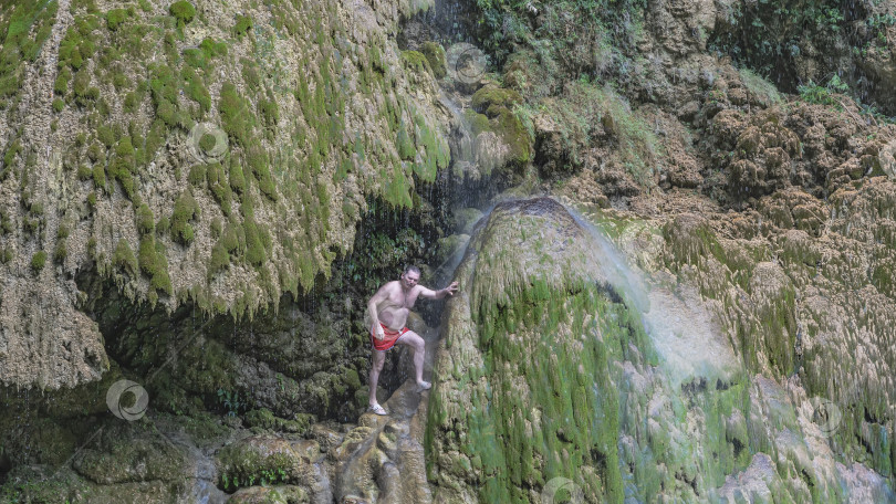 Скачать Живописный водопад. Тонкие струйки воды стекают по покрытым мхом террасам, образуя завесу. фотосток Ozero