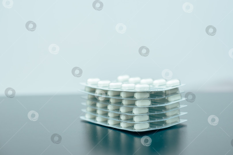 Скачать Стопка блистеров с белыми таблетками на столе фотосток Ozero
