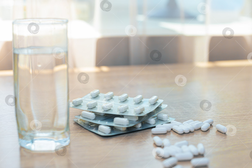 Скачать Таблетки, медикаменты и стакан воды на деревянном столе фотосток Ozero