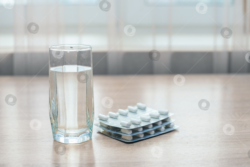 Скачать Таблетки, медикаменты и стакан воды на деревянном столе фотосток Ozero