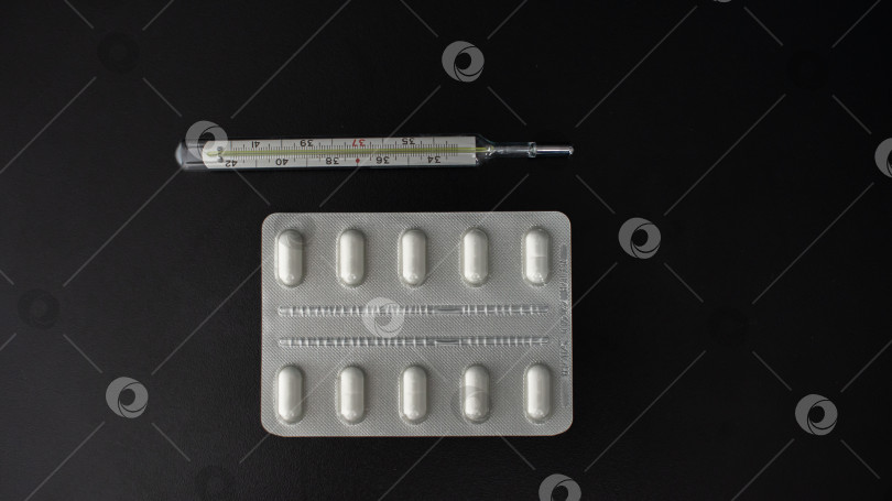 Скачать Таблетки, медикаменты, градусник на черном столе фотосток Ozero