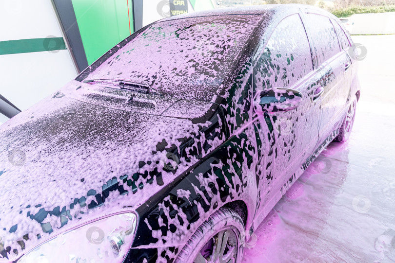 Скачать Водитель-Мужчина Наносит Розовую Пену На Черную автомойку На Автомойке Для Ухода За Автомобилем фотосток Ozero