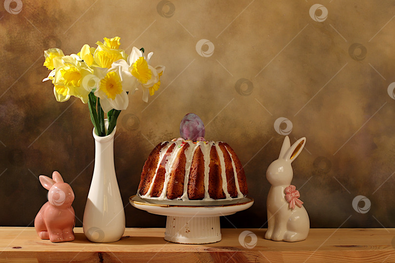 Скачать Концепция празднования Пасхи, традиционный пасхальный кулич, фигурки пасхальных кроликов и весенние нарциссы в вазе на фоне элегантной кухни, идеи пасхальных блюд для домашней кухни, шаблон дизайна фотосток Ozero