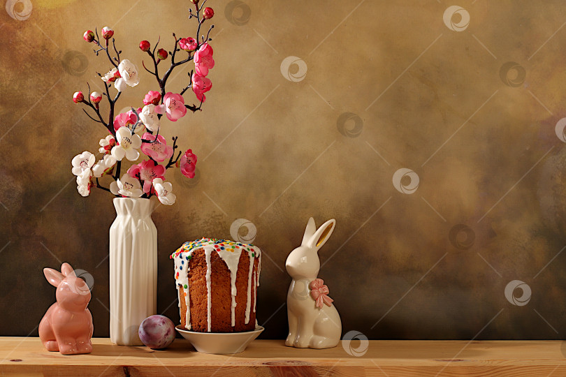 Скачать Традиционный пасхальный кулич, фигурки пасхальных кроликов и ветки сакуры в вазе на фоне элегантной кухни, концепция празднования Пасхи, идеи пасхальных блюд для домашней кухни, шаблон дизайна фотосток Ozero