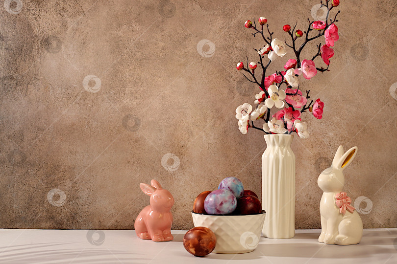Скачать Концепция празднования Пасхи, расписные яйца, фигурки пасхальных кроликов и ветки сакуры в вазе на фоне элегантной кухни, идеи пасхальных блюд для домашней кухни, шаблон дизайна фотосток Ozero