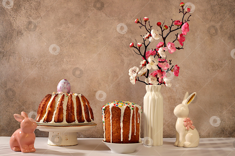 Скачать Концепция празднования Пасхи, традиционный пасхальный кулич, фигурки пасхальных кроликов и ветки сакуры в вазе на фоне элегантной кухни, идеи пасхальных блюд для домашней кухни, шаблон дизайна фотосток Ozero