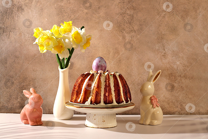 Скачать Концепция празднования Пасхи, традиционный пасхальный кулич, фигурки пасхальных кроликов и весенние нарциссы в вазе на фоне элегантной кухни, идеи пасхальных блюд для домашней кухни, шаблон дизайна фотосток Ozero