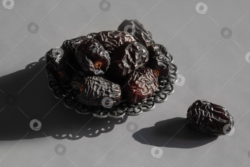 Скачать Темные сушеные финики в богато украшенной миске, один рядом фотосток Ozero