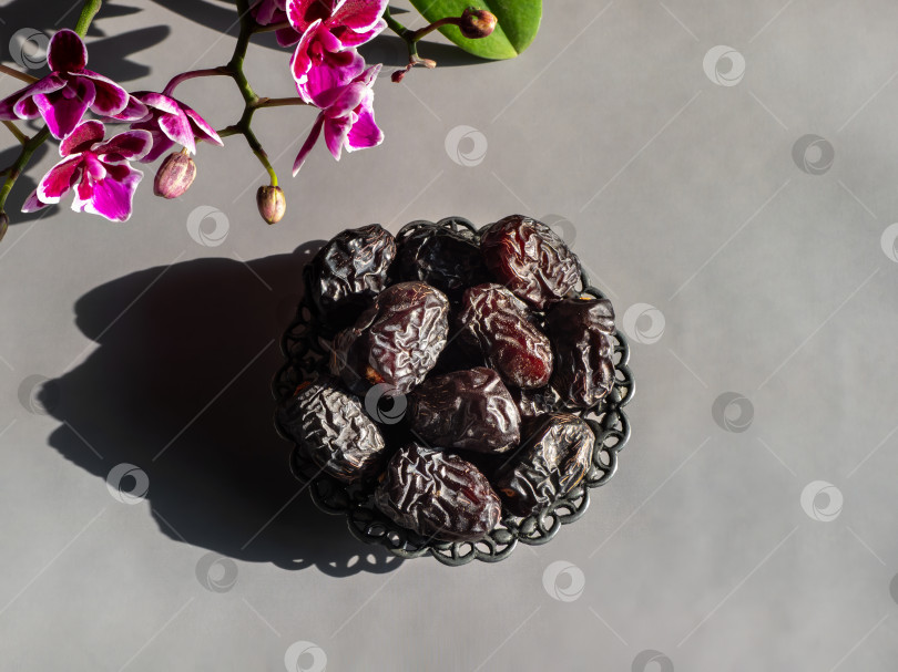 Скачать Темные сушеные финики лежат в изящной металлической миске фотосток Ozero