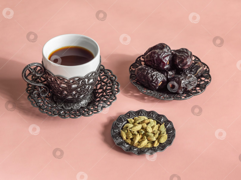 Скачать Чашка кофе с кардамоном стоит рядом с сушеными финиками и фруктами фотосток Ozero